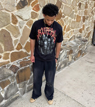 Load image into Gallery viewer, Person wearing a graphic t-shirt leaning against a stone wall.
